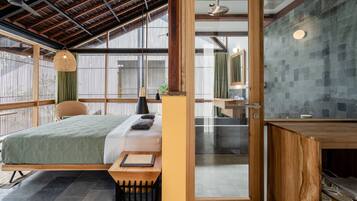 A modern bedroom with a bed, bedside table, and a view through a glass door to a bathroom.