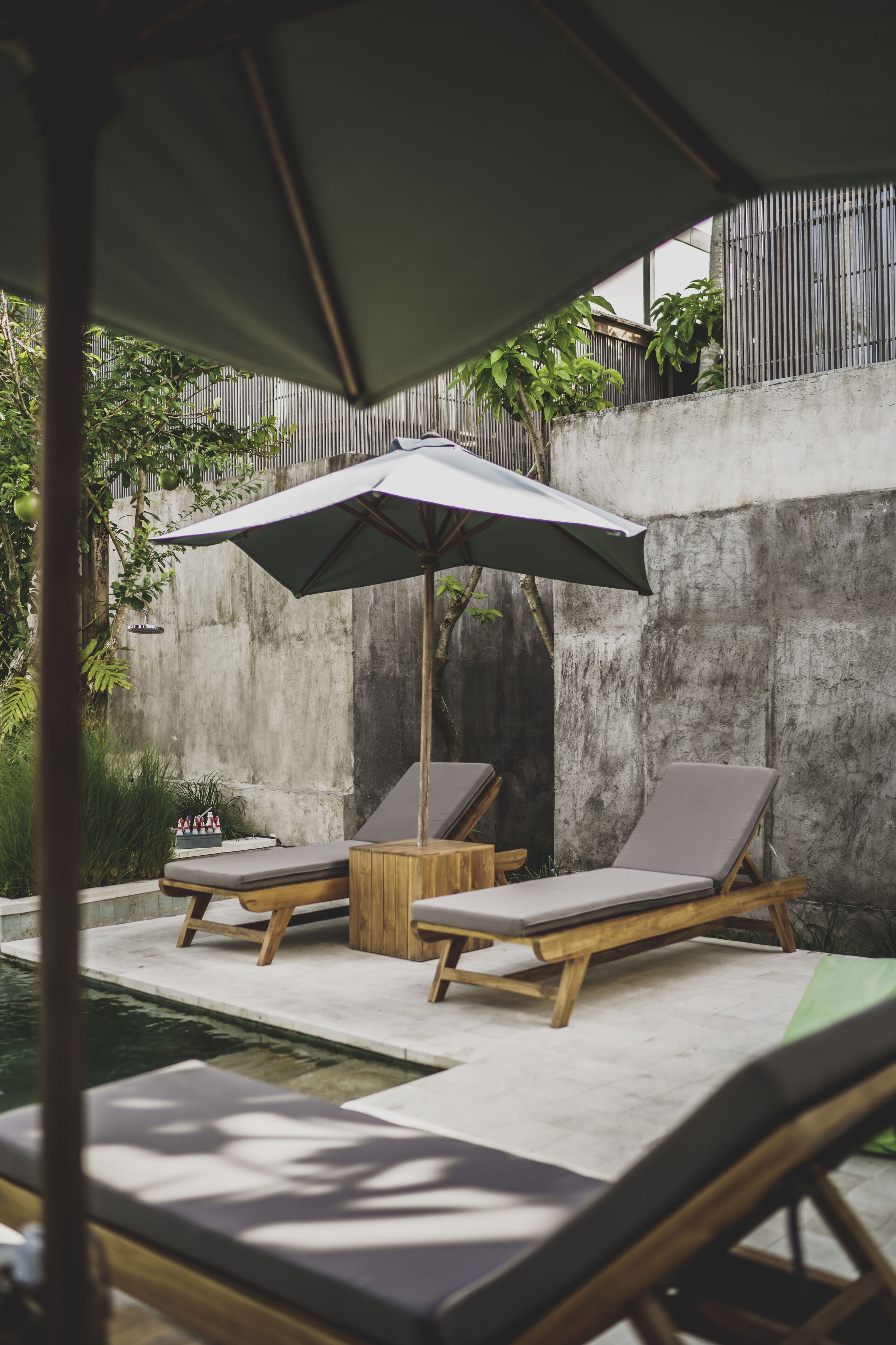 A poolside area with two lounge chairs and a large umbrella.