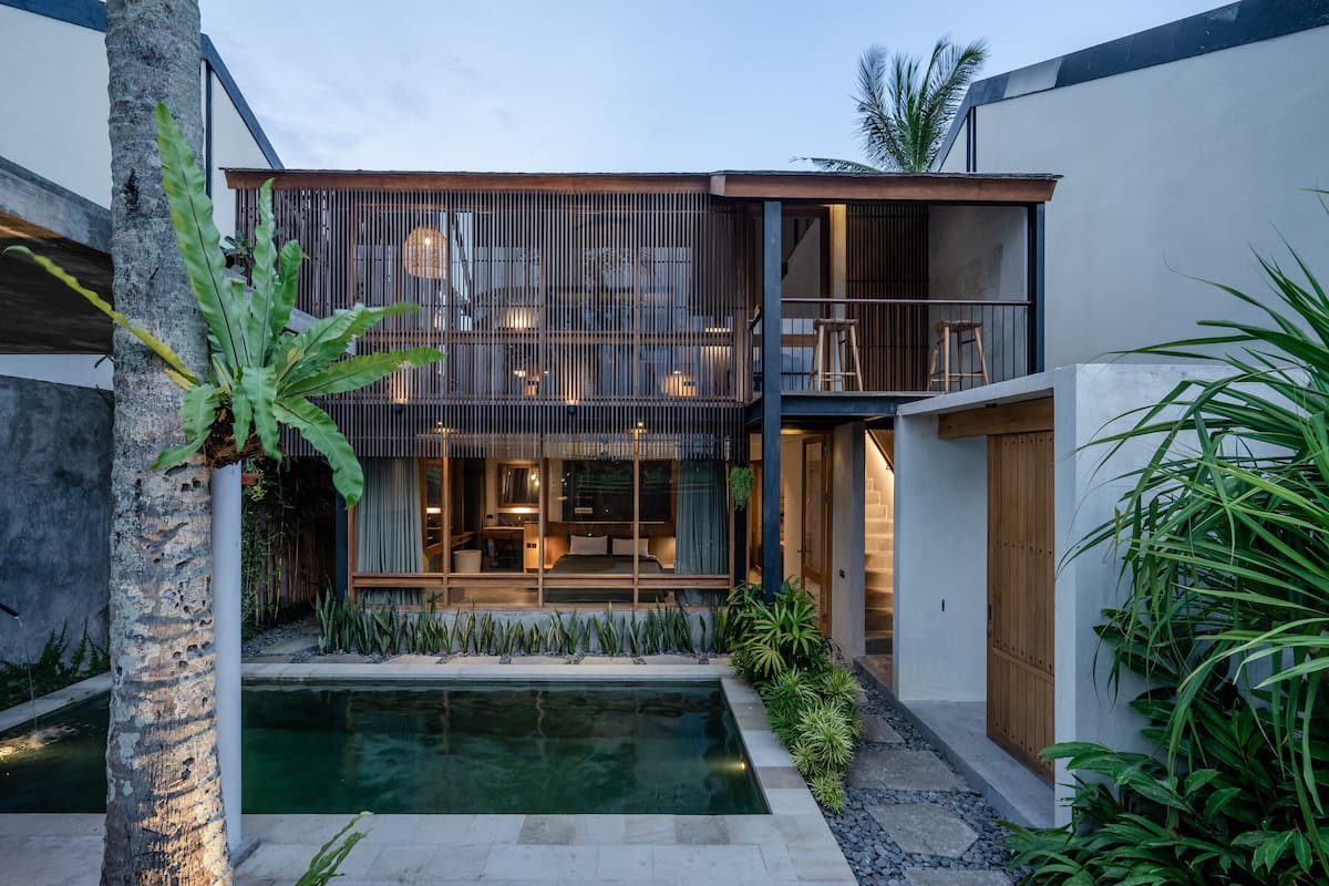 A modern two-story house with a pool, wooden deck, and lush greenery.