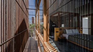 A modern hotel room with a wooden slatted wall, a bed, and a small bedside table. - The Saren (Tabanan)