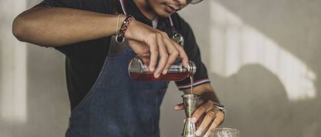 A person pouring a drink into a glass on a bar counter.