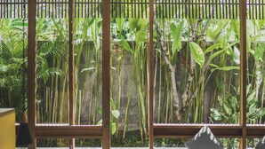 A room with a view of a pool, wooden blinds, and a bed with pillows. - The Saren (Tabanan)