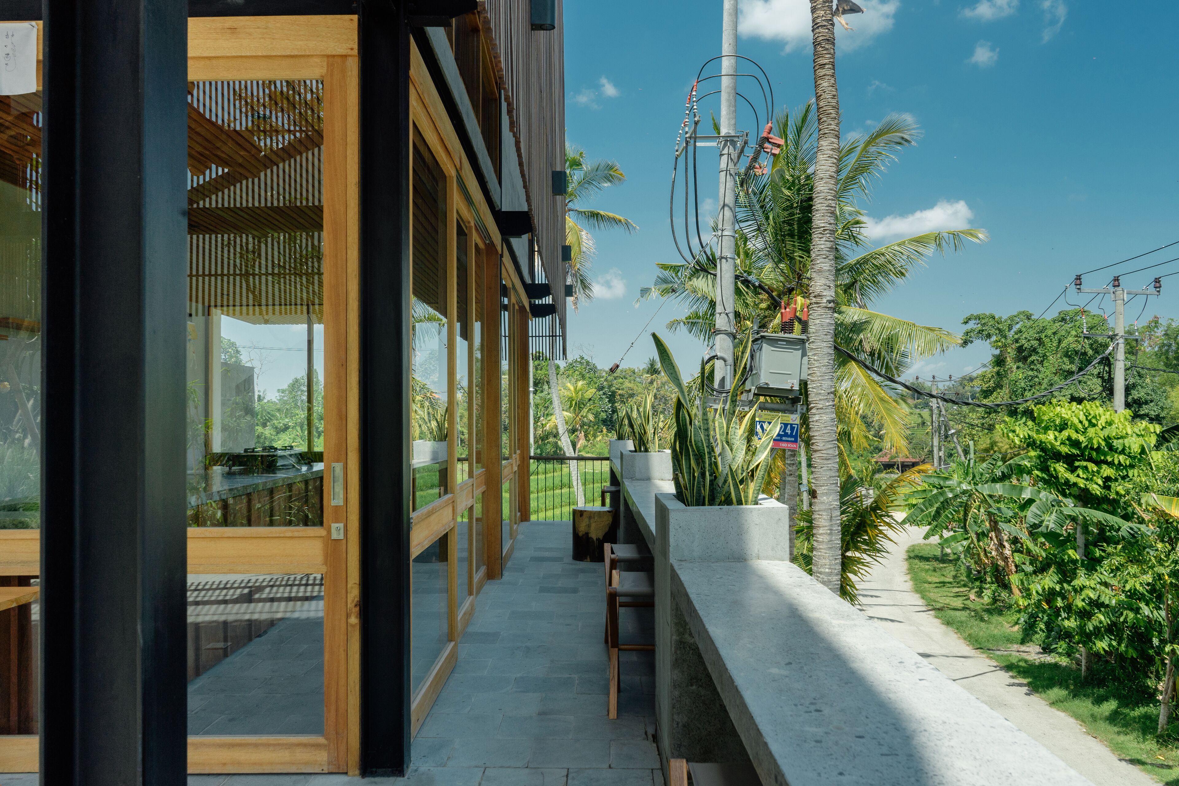A modern building with large windows, a wooden deck, and a concrete planter with plants.