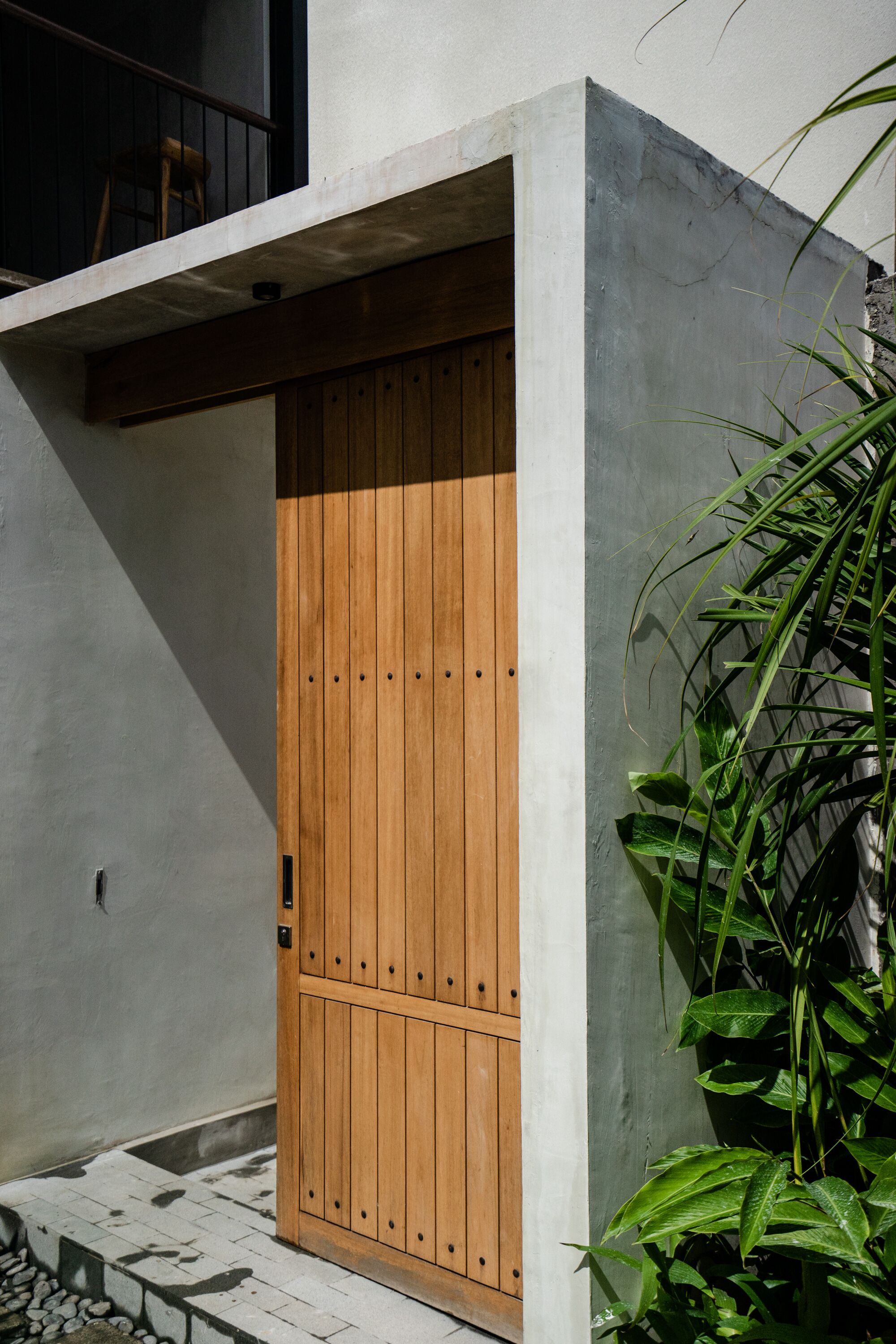Una puerta de madera con manija de metal, incrustada en una pared de concreto con un escalón que lleva a ella.