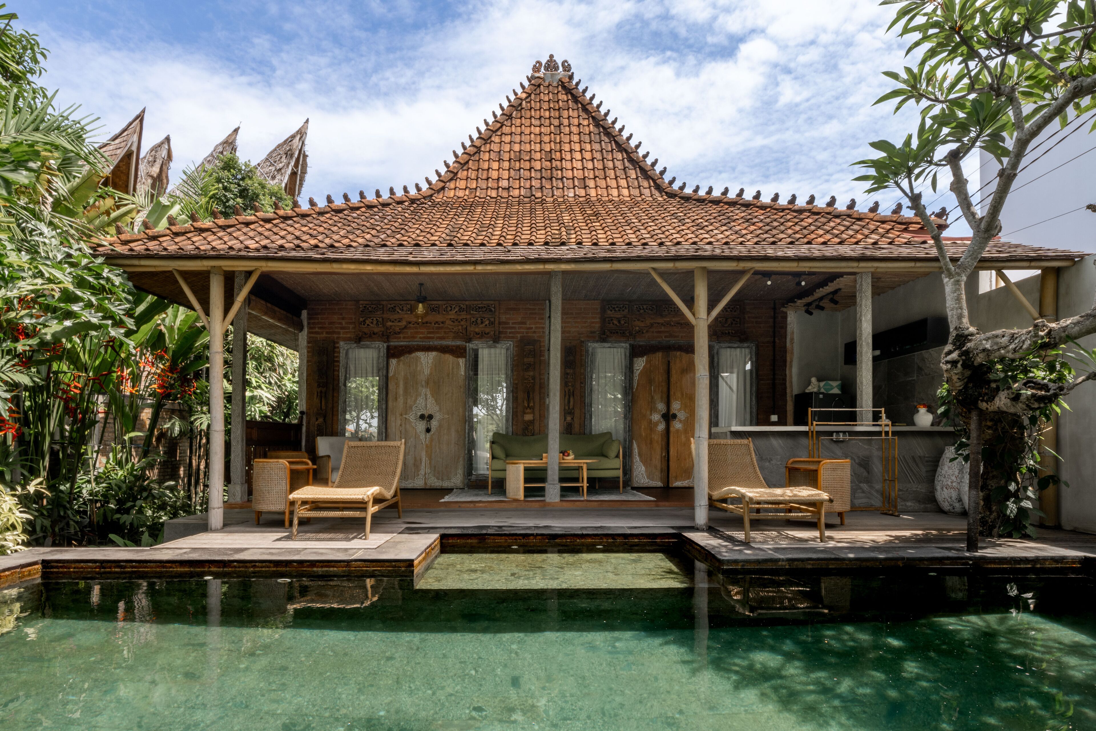 A traditional house with a tiled roof, a swimming pool, and outdoor seating.