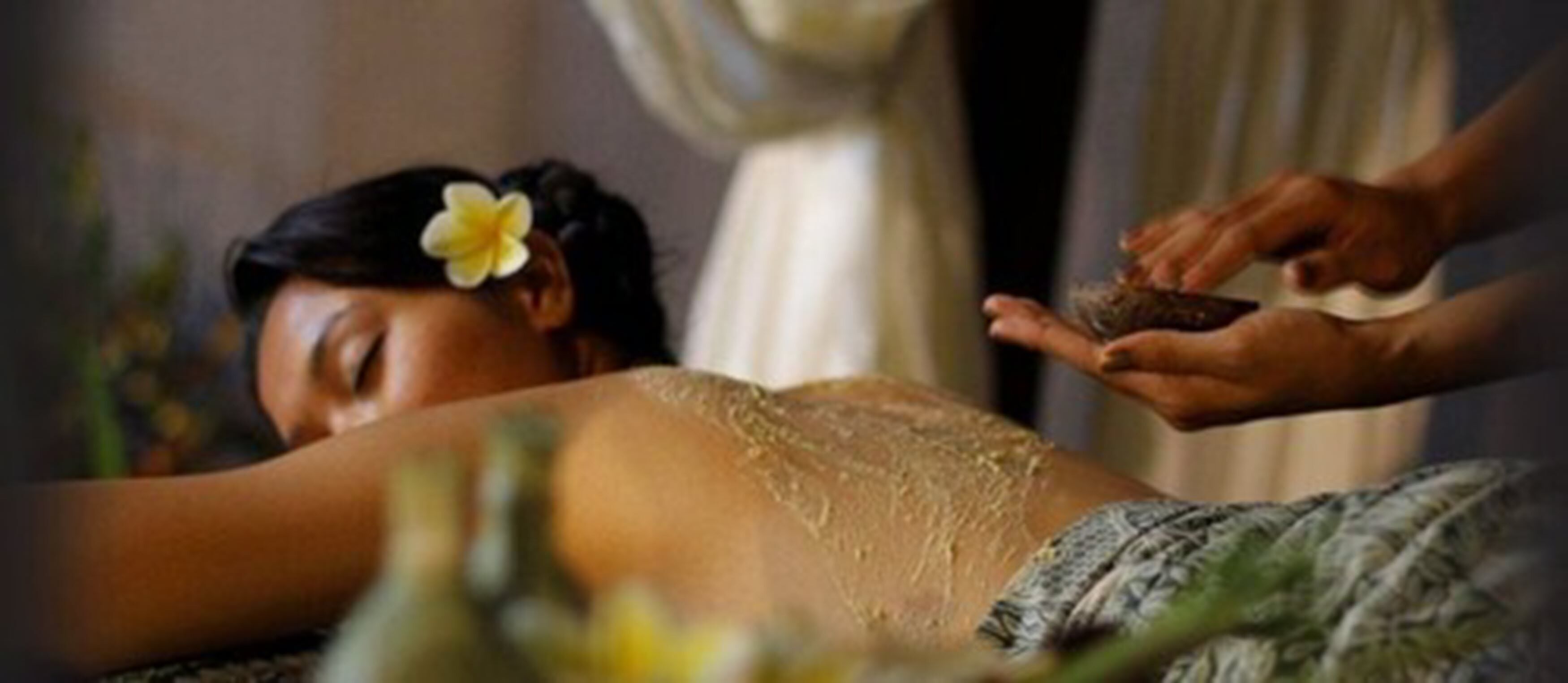 A person receiving a massage with a flower in their hair.
