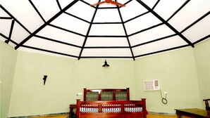 Une pièce avec un plafond haut, un lit, une table et un climatiseur fixé au mur.