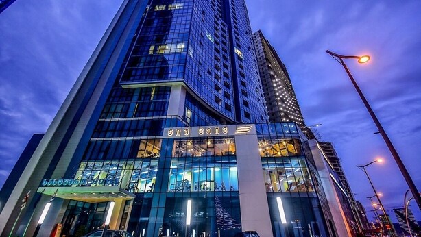 A modern hotel with a glass facade, a prominent entrance, and a sign indicating it is a hotel.