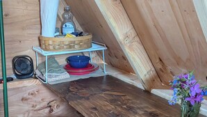 Une table de salle à manger en bois, accompagnée de deux tabourets, un panier tressé contenant divers objets et un vase avec des fleurs, le tout placé dans un coin.