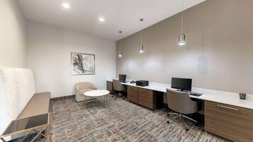 Un espace de bureau moderne comprenant un grand bureau, deux chaises, une petite table ronde et un banc.