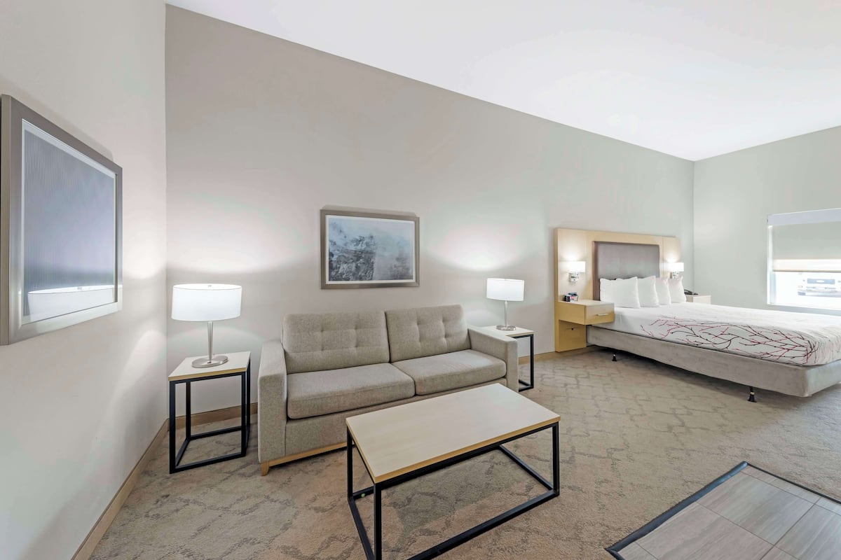 A hotel room with a sofa, a bed, a coffee table, and two bedside tables with lamps.