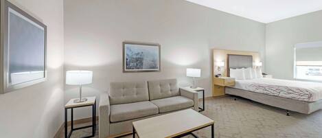 A hotel room with a sofa, a bed, a coffee table, and two bedside tables with lamps.