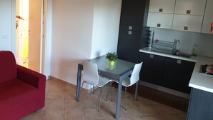 A compact kitchen with a dining area, a red sofa, and a potted plant.