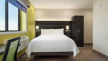 Une chambre d’hôtel avec un grand lit, des lampes de chevet, une armoire et une fenêtre avec des stores.