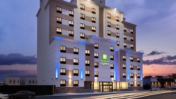 Ein mehrstöckiges Holiday Inn Express Hotel mit moderner Fassade, beleuchteten Fenstern und dem markanten grünen Logo.