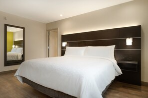 Ein Hotelzimmer mit einem großen Bett, einem dunklen Kopfteil und einem Spiegel an der Wand.