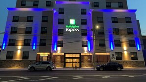 Un edificio de Holiday Inn Express con un diseño moderno, que destaca un letrero y una iluminación azul iluminada.
