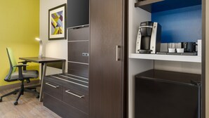 Ein kleines Hotelzimmer mit Küchenzeile, Schreibtisch und Stuhl.