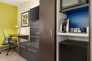 Une chambre d’hôtel compacte comprenant un coin cuisine, un bureau et une chaise.