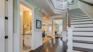 A spacious hallway with a staircase, wooden flooring, and white walls. - Spacious 2700 Sq Ft 30A Home - Golf Cart and 6 Bikes, Resort Pool - Life's a Beach in NatureWalk (Santa Rosa Beach)