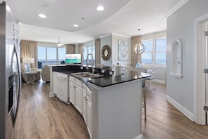 A modern kitchen with a central island, white cabinetry, and a view to the outside.