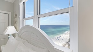 A bed with a view of the beach through large windows. - Sunrise 2011 • Gulf-Front 3BR Retreat • Beach Service (Panama City Beach)