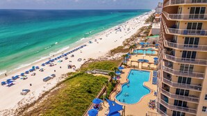 A beachfront hotel with a swimming pool, beach umbrellas, and a pier in the background. - Sunrise 2011 • Gulf-Front 3BR Retreat • Beach Service (Panama City Beach)