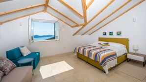 Een slaapkamer met een bed, een raam met uitzicht, een bank en een nachtkastje.