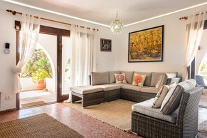 A living room with a sectional sofa, a large painting, and a potted plant.