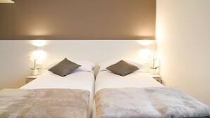 Una cama doble con dos almohadas, una mesita de noche con lámpara y una lámpara de pared.