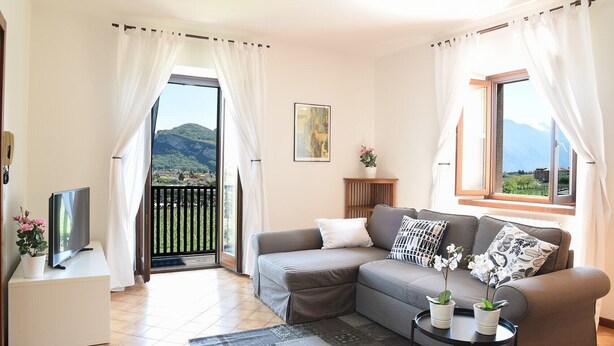 Una sala de estar con un sofá, un televisor, una mesa con una planta y vistas a las montañas a través de la ventana.