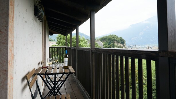 Un balcon avec une table, deux verres et une bouteille de vin.