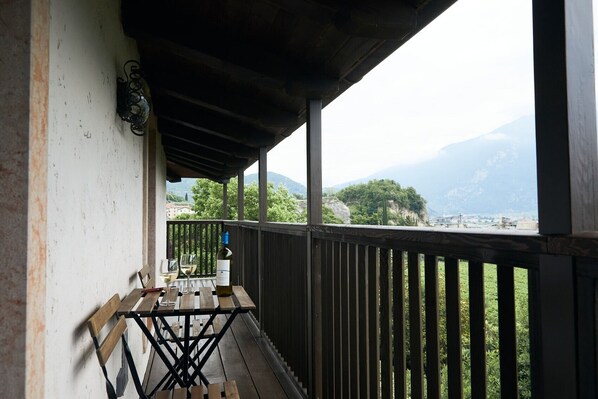 A balcony with a table, two glasses, and a bottle of wine.