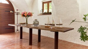 Un intérieur rustique avec une table en bois, un vase rempli de fleurs et des maquettes de bateaux.