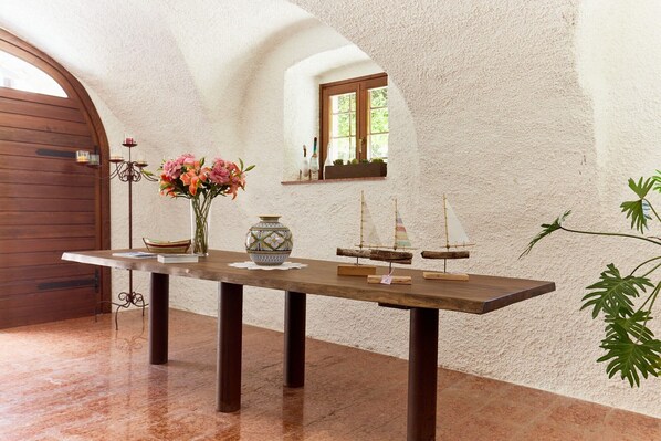 Un intérieur rustique avec une table en bois, un vase rempli de fleurs et des maquettes de bateaux.