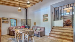 A spacious living area with a dining table, sofas, and a staircase leading to an upper level.