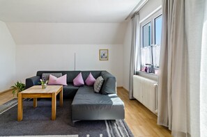 Uma sala de estar moderna com um sofá modular, uma mesa de centro de madeira e um radiador.