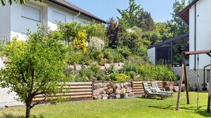 Ein Haus mit Garten, Schaukel und einer Steinmauer.