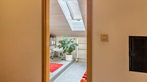 Ein Zimmer mit einer Dachfensterkuppel, einem Blumentopf, einem roten Teppich und einem weißen Stuhl.