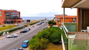 Un hotel con vista sul mare, un parcheggio e una strada con auto.