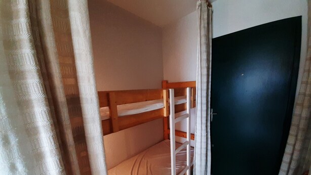 Una stanza con un letto a castello, una porta e tende.