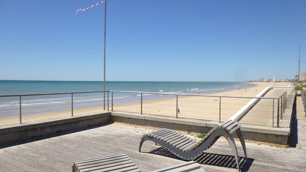 A wooden deck with metal railings overlooking a beach.