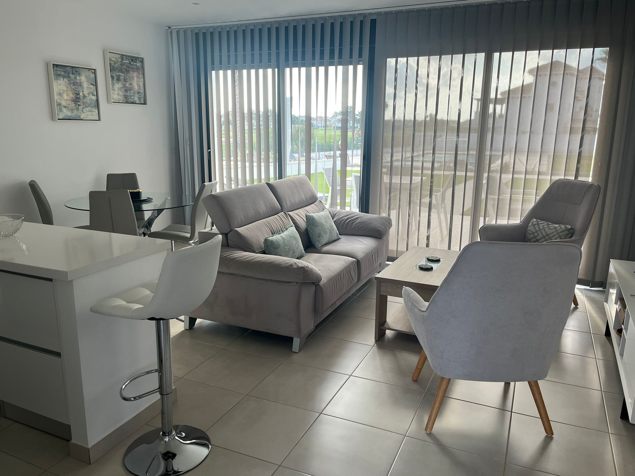 A modern living room with a sofa, a coffee table, a dining table, and a TV.