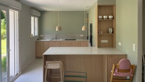Eine moderne Küche mit einer zentralen Kochinsel, Holzschränken und einem Essbereich mit Stühlen.