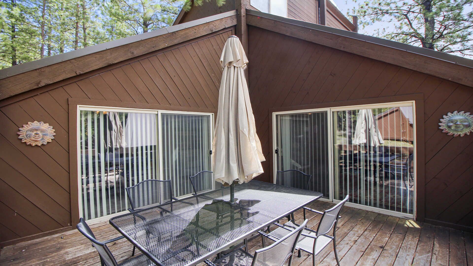 A covered patio with a metal table and chairs, a large umbrella, and sliding glass doors.