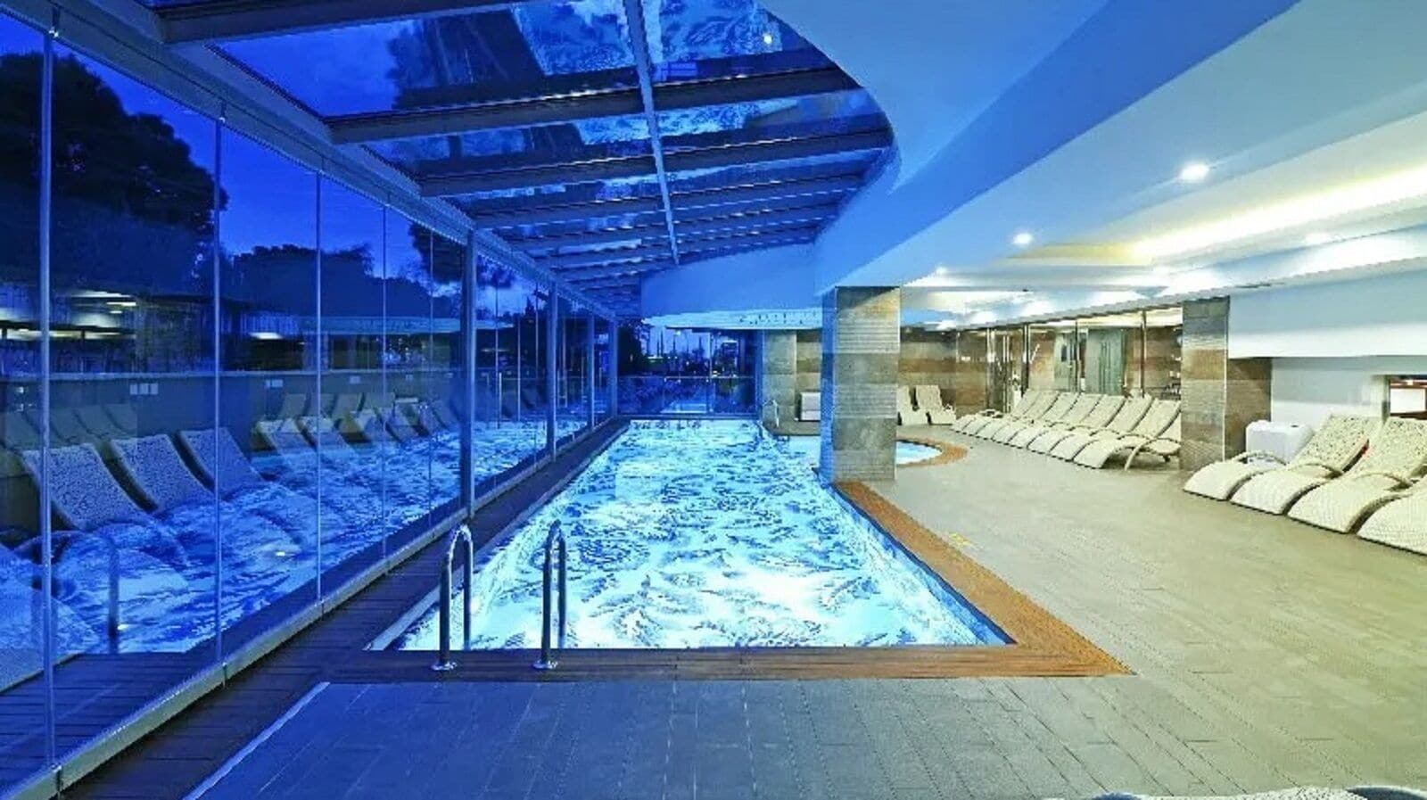 Una piscina cubierta, una piscina al aire libre, sombrillas, tumbonas