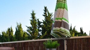 An outdoor patio with a table and two chairs, a potted plant, and a striped umbrella. - T2 Les Lilas ,plage 300m (Hyères)