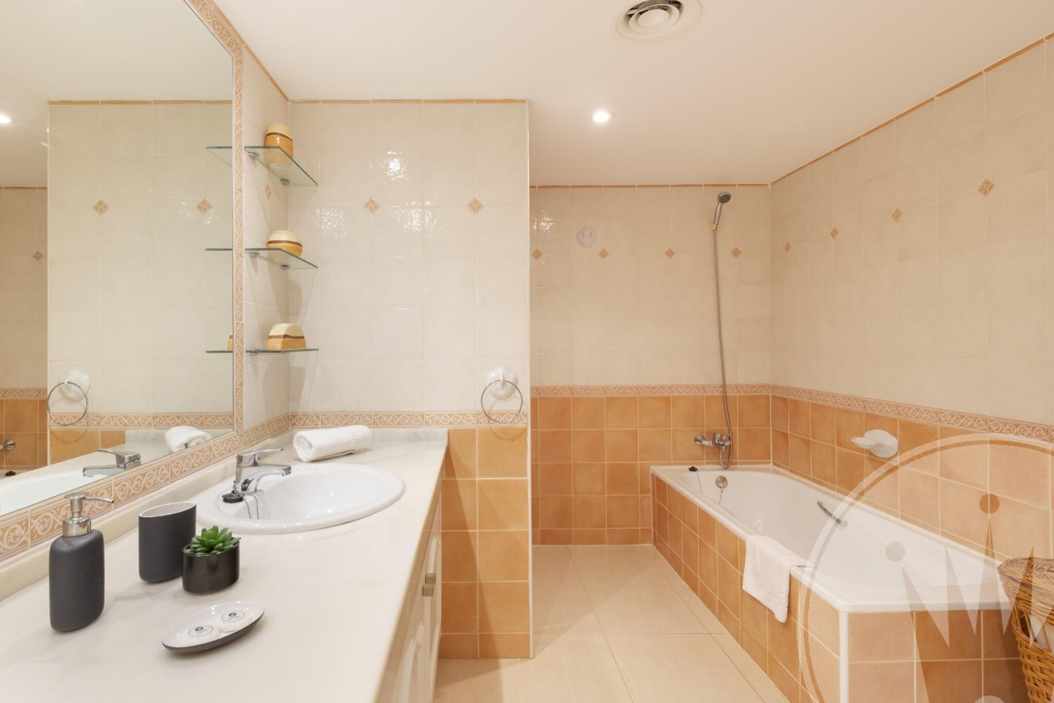Ein modernes Badezimmer mit großem Spiegel, zwei Waschbecken, einer Badewanne und einer Dusche.