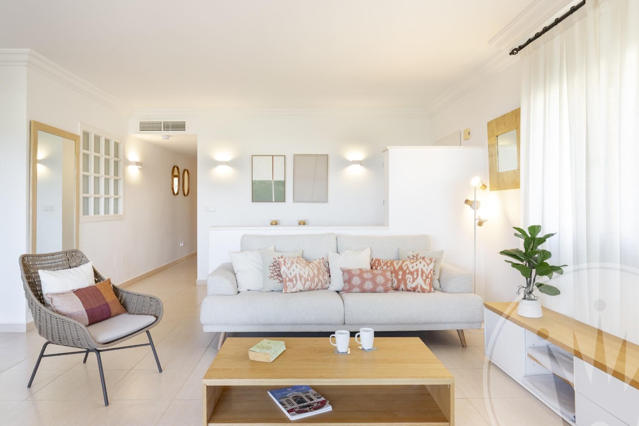 Un salon moderne avec un canapé, un fauteuil, une table basse et des coussins décoratifs.
