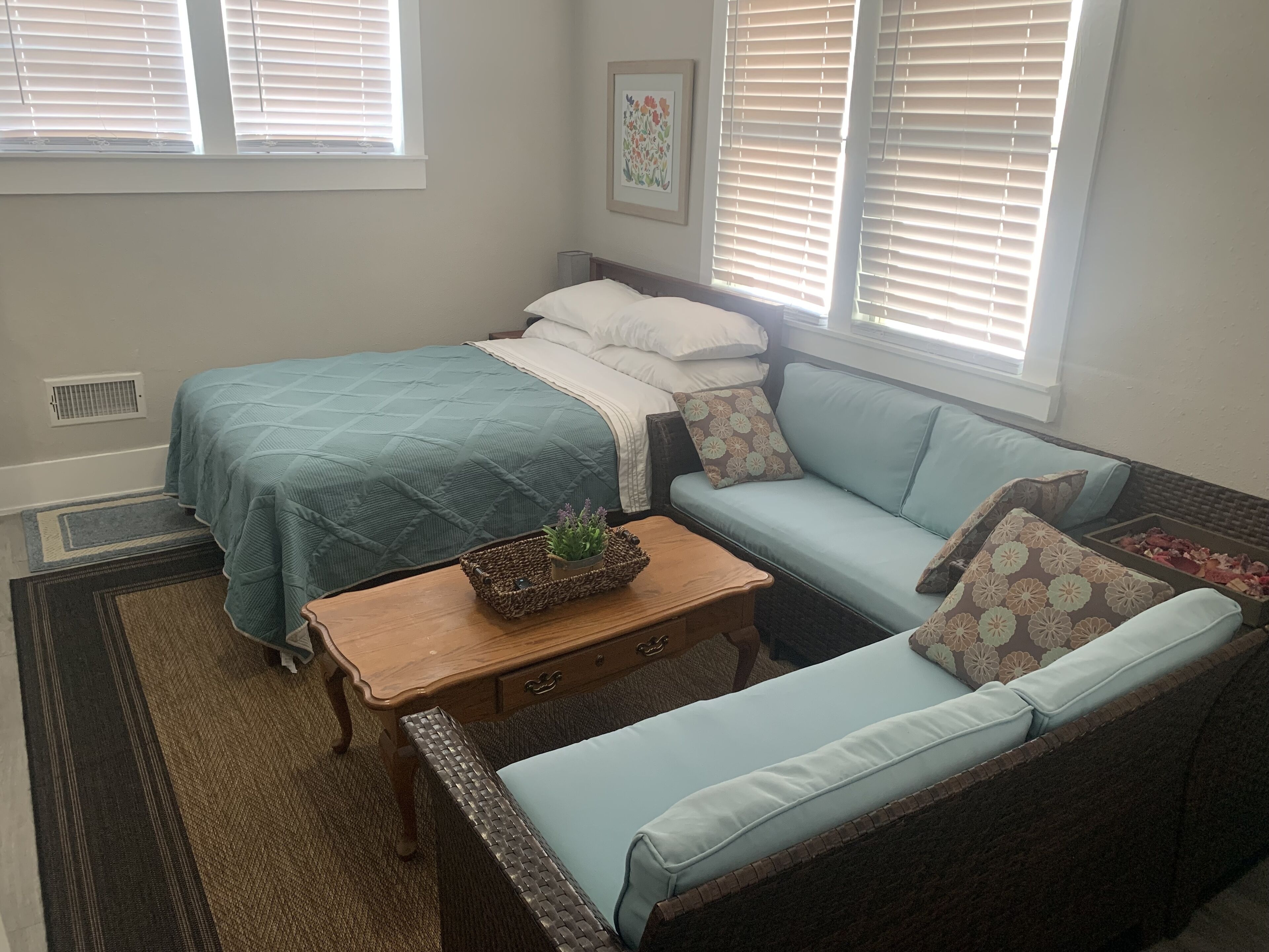 Un dormitorio con cama, sofá, una mesita y una ventana con persianas.